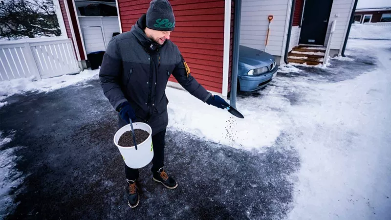 Mies hiekoittamassa pihaa Leca-murskeella.